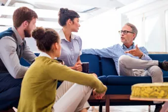 Quatre personnes sur et autour de la chaise discutant de quelque chose.