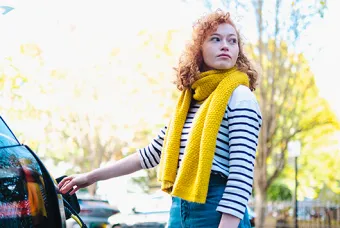Vrouw met gele sjaal laadt elektrische auto op