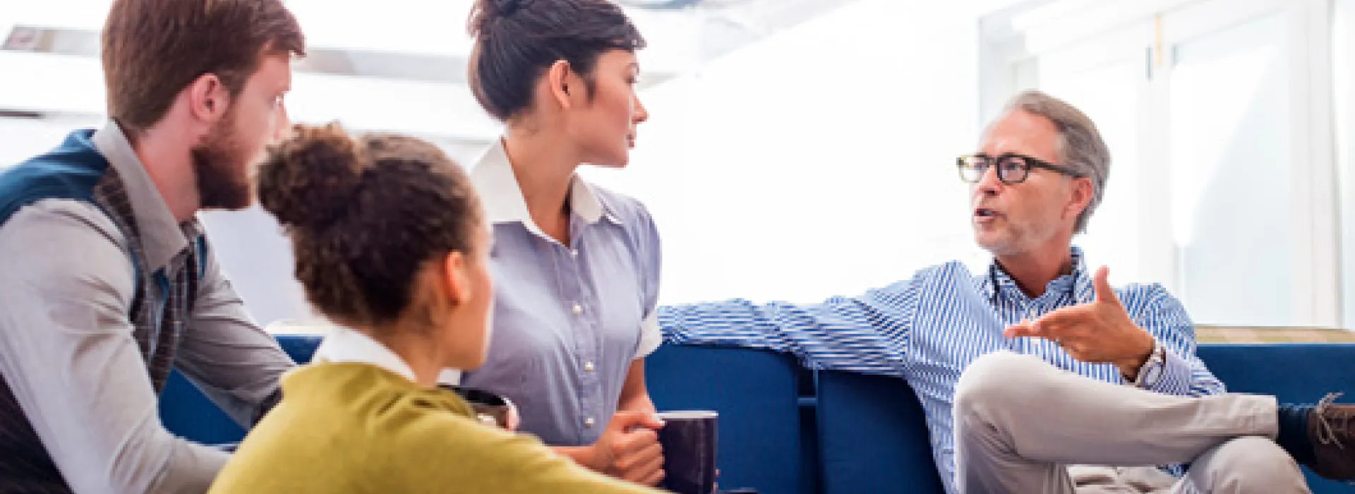 Vier mensen op en rond de stoel die iets bespreken...